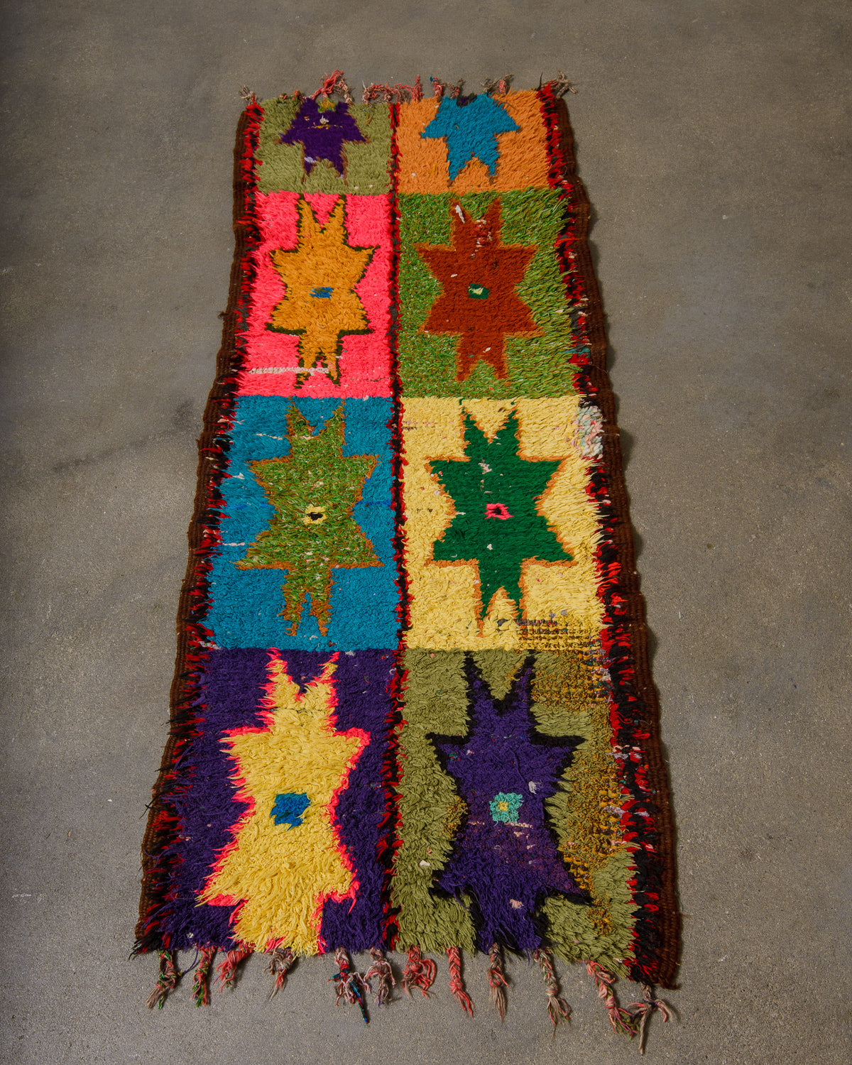 Vintage boucherouite rug laying on concrete floor.